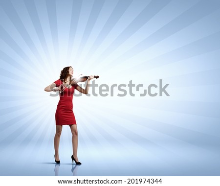 Young attractive woman in red dress playing violin