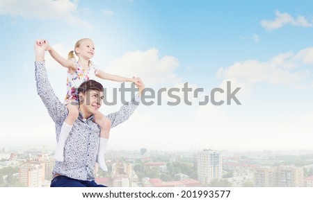 Little daughter sitting on father\'s shoulders. Parenting concept