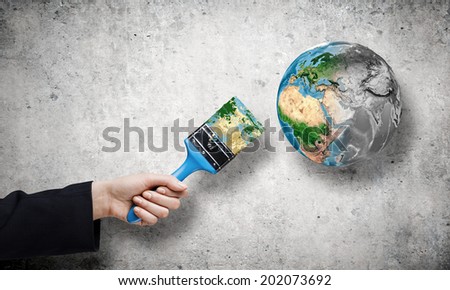 Close up of hand painting Earth planet with brush. Elements of this image are furnished by NASA