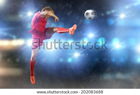 Young football player on stadium kicking ball