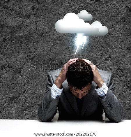Depressed young businessman sitting wet under rain