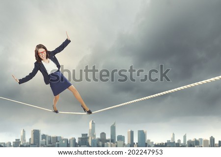 Young businesswoman balancing on rope above city