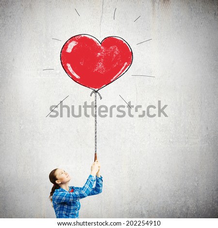 Young woman in casual holding heart shaped balloon