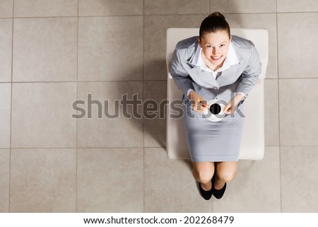 Top view of busineswoman sitting on chair with cup of coffee