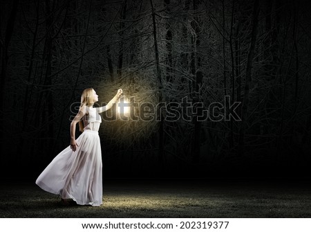 Young woman in white long dress walking in night wood