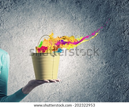 Close up of female hand holding bucket with colorful splashes