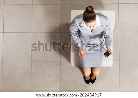 Top view of businesswoman sitting on chair with mobilephone in hand