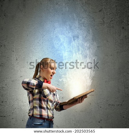 Woman in casual wear holding opened book in hands