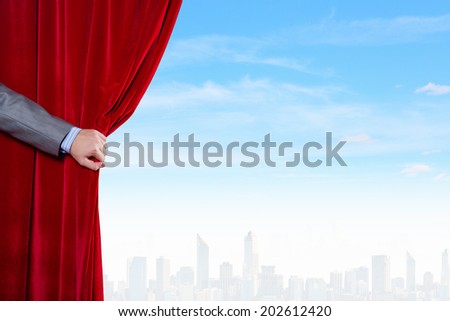 Hand of businessman opening red velvet curtain