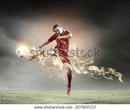 Young football player on stadium kicking ball in jump
