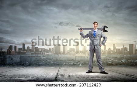 Young determined businessman with wrench in hands