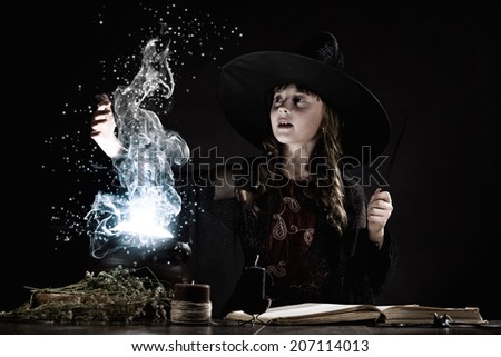 Little Halloween witch making magic with stick