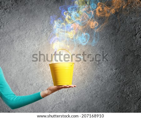 Close up of female hand holding bucket with colorful fumes