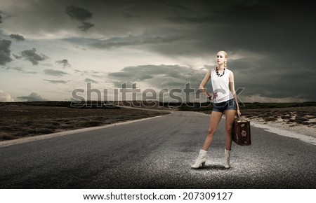 Young woman hiker standing with suitcase in hand