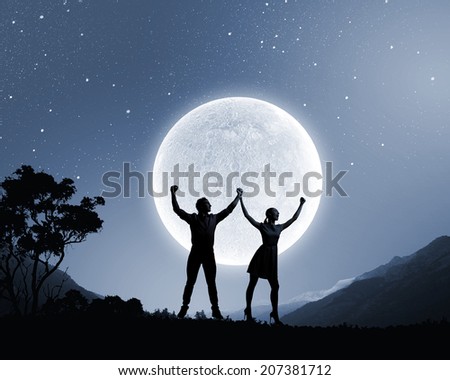 Silhouettes of young couple against full moon