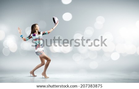 Young woman in colored dress and hat dancing against bokeh background
