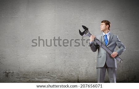 Young determined businessman with wrench in hands