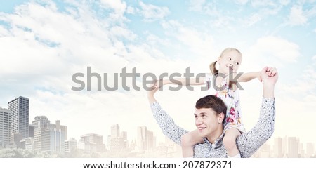 Little daughter sitting on father's shoulders. Parenting concept
