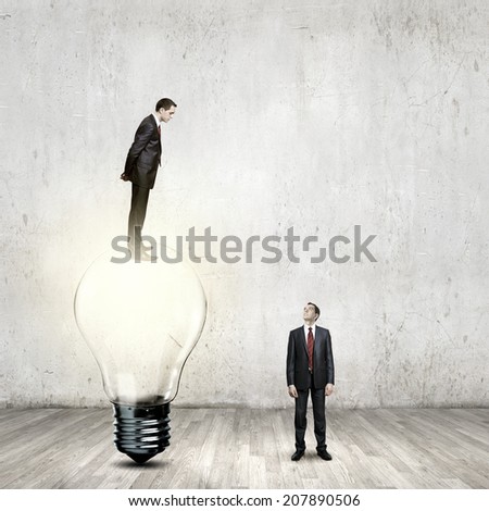 Businessman standing on top of light bulb and looking down