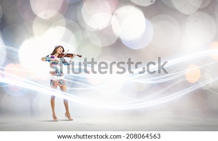 Young attractive woman in colored dress playing violin