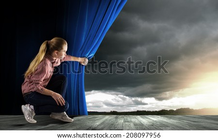 Young woman in casual opening blue curtain and looking at sky