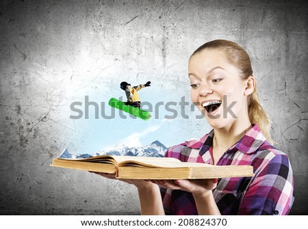 Young woman looking in opened book and snowboarder making jump