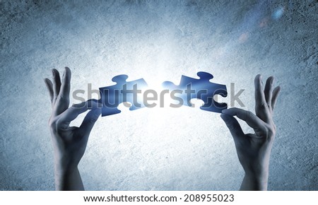 Close up image of hands connecting puzzle elements