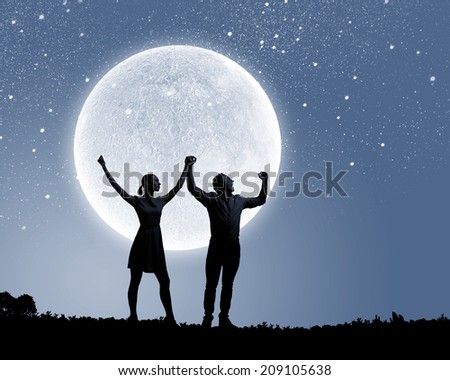 Silhouettes of young couple against full moon