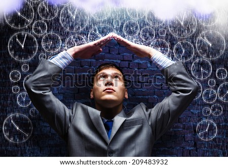 Young businessman under rain covering head with hands