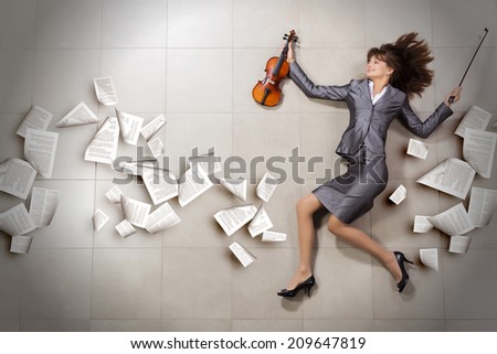 Attractive businesswoman with violin in hands and papers flying in air