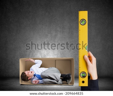Close up of business person hand measuring man in carton box