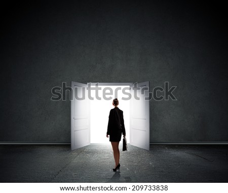 Silhouette of businesswoman with briefcase standing in doorway