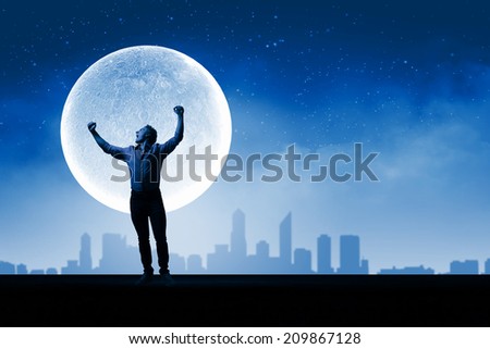 Young screaming man at night with big full moon at background