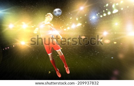 Young football player on stadium kicking ball with head in jump