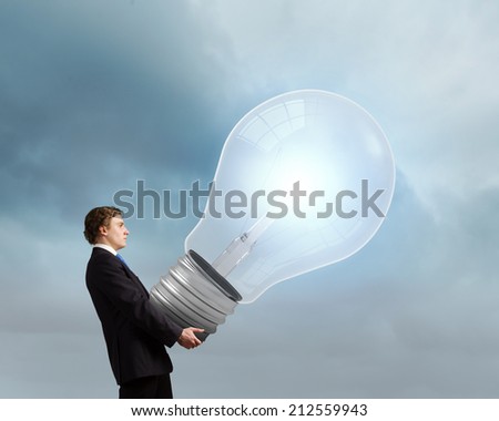 Young businessman carrying in hands big light bulb