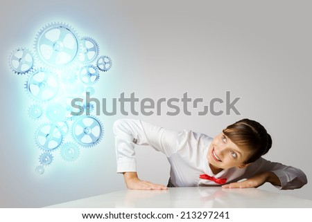 Businesswoman leaning on table and looking at cogwheels