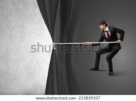 Young businessman pulling curtain with rope. Place for text