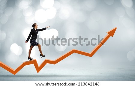Young cheerful businesswoman walking on increasing graph