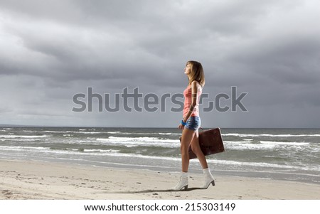 Young pretty woman walking with suitcase in hand