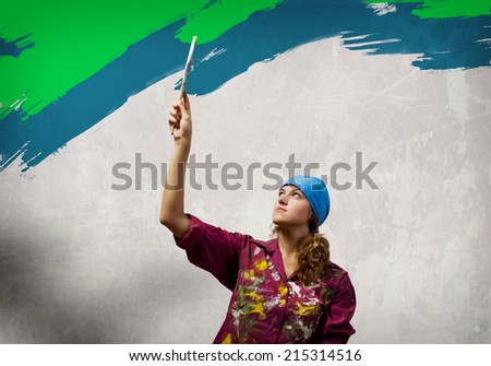 Young woman painting wall in colors with brush