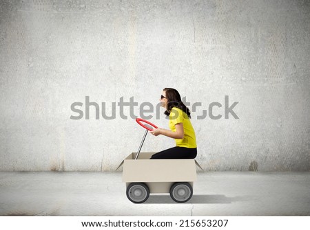 Young funny woman riding in carton box