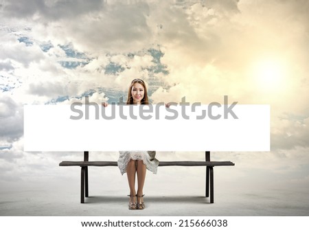 Young asian woman sitting on bench with blank banner