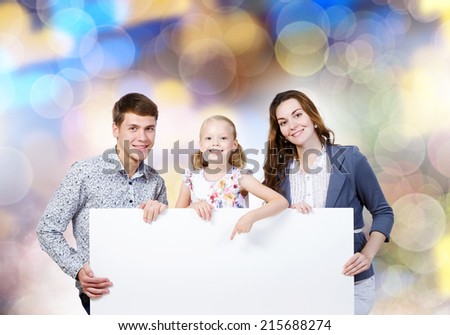 Happy family of three holding white blank banner. Place for text
