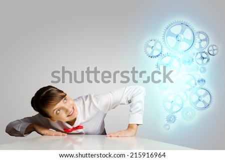 Businesswoman leaning on table and looking at cogwheels