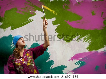 Young woman painting wall in colors with brush
