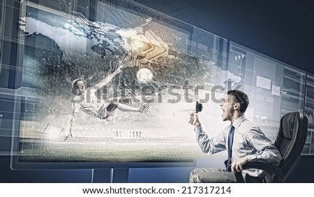 Young man screaming in megaphone and watching football match