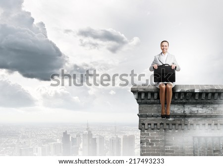 Young pretty businesswoman sitting on top of building high above city