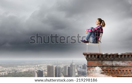 Young woman in casual sitting on in chair on top of building