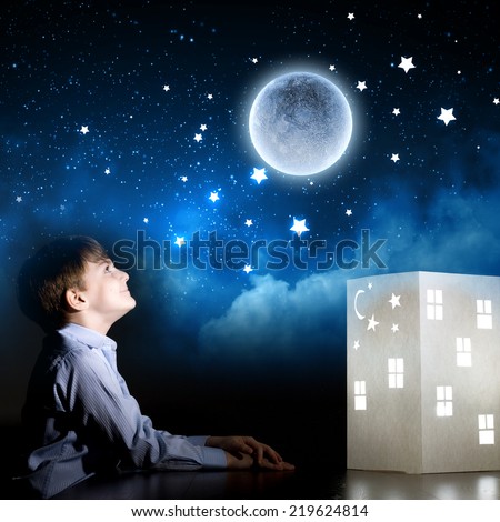 Cute little boy in dark room dreaming about home and family
