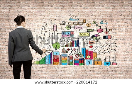Rear view of businesswoman coloring business sketches with paint brush